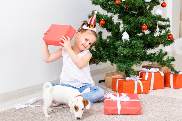 Kerstmis, huisdieren en vakantieconcept - Kind in santahoed met een Jack Russell Terrier-puppy