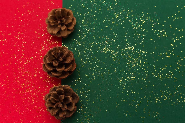 Kerstmis met dennenappels en goud schijnt glitter op traditionele groene en rode achtergrond.