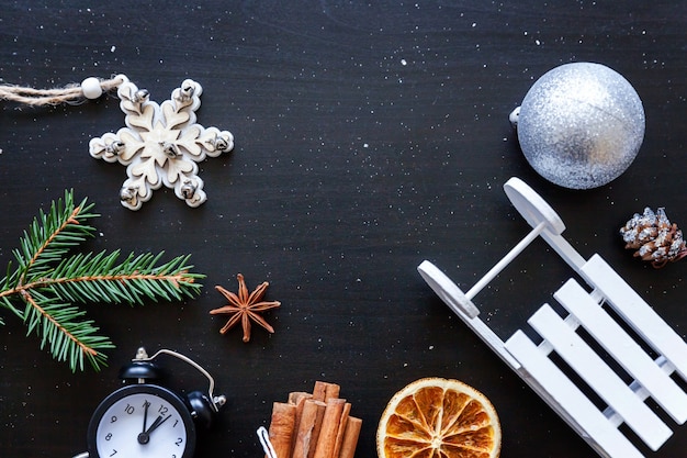 Kerstmis Nieuwjaar Samenstelling frame gemaakt van winter objecten fir branch ornament wekker slee op donkere zwarte achtergrond. Plat lag bovenaanzicht kopieerruimte. Kerst december tijd voor viering concept