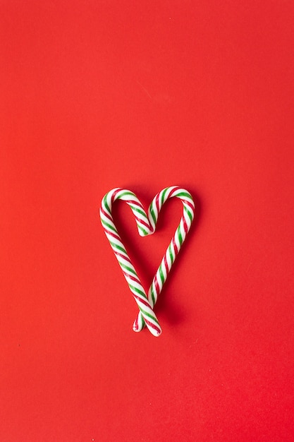 Kerstmis-nieuwjaarsamenstelling. hartsymbool gemaakt van snoepgoed stokken op rood