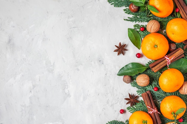 Kerstmis of gelukkig Nieuwjaar achtergrond gemaakt van fir tree takken, mandarijnen, noten en bessen op concrete achtergrond. plat leggen. bovenaanzicht met kopie ruimte