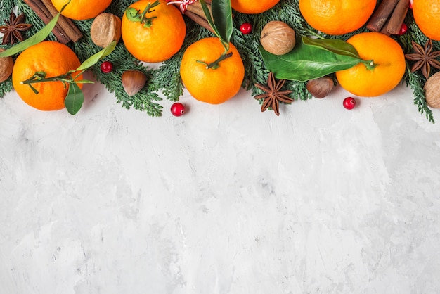 Kerstmis of gelukkig Nieuwjaar achtergrond gemaakt van fir tree takken, mandarijnen, noten en bessen op concrete achtergrond. plat leggen. bovenaanzicht met kopie ruimte