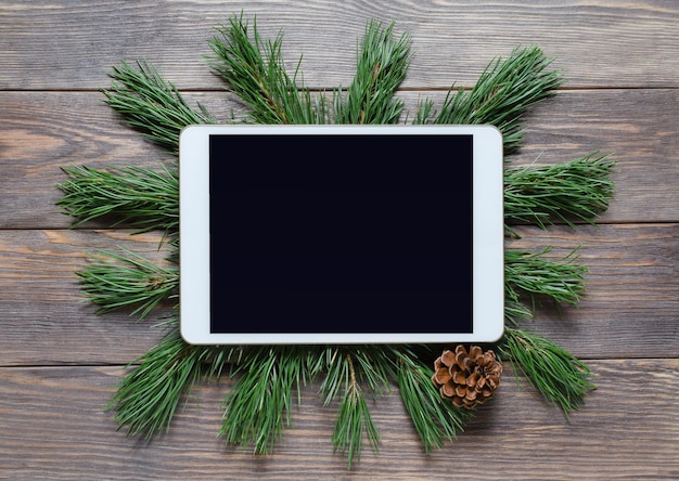 Kerstmis of Nieuwjaar achtergrond op een houten achtergrond. Tablet met een leeg scherm voor groeten. Plat lag, bovenaanzicht, kopieer ruimte.