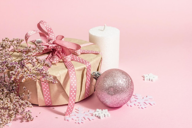 Kerstmis of Nieuwjaar cadeau concept in roze tinten. Wikkeldoos, gebonden strik, droogbloemen en feestelijk speelgoed. Zero Waste-stijl, trendy hard licht, donkere schaduw, roze achtergrond, kopieerruimte