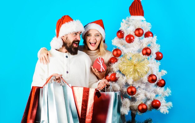 Kerstmis of nieuwjaar winkelen gelukkig paar met shopper tassen in de buurt van kerstboom verkoop korting