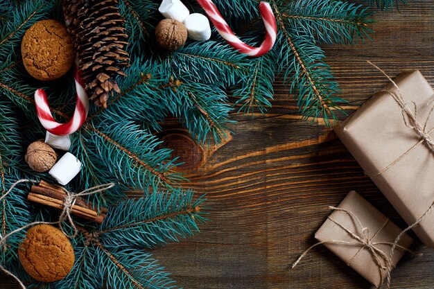 Kerstmis of nieuwjaarsachtergrond met koekjeskruiden, kaneelnoten en dennenboomtak op donker hout...