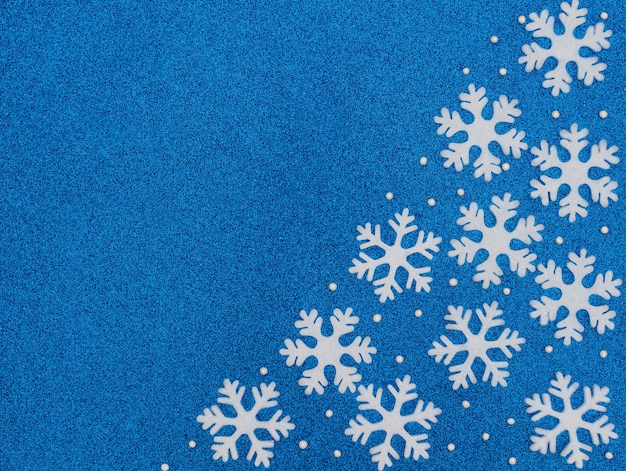 Kerstmis of winter blauwe achtergrond met witte sneeuwvlokken en kralen. Plat lag stijl met kopie ruimte.