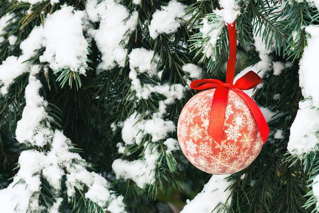 Kerstmis rode bel als achtergrond op sneeuwboom