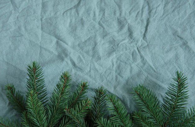 Kerstmis uitstekende achtergrond. Vuren twijgen op de groene linnen verfrommelde textielachtergrond