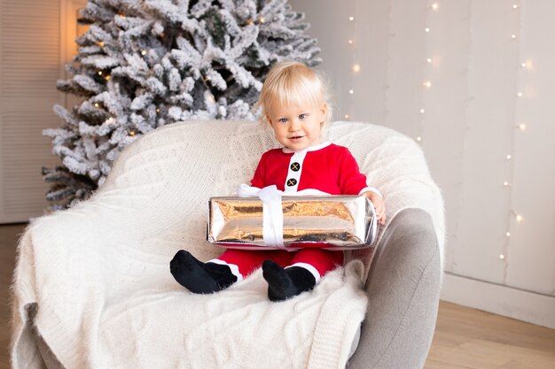 Kerstmis, vakantie en kindertijd concept. Schattige kleine jongen in de buurt van kerstboom. Magische feestelijke decoratie voor thuis