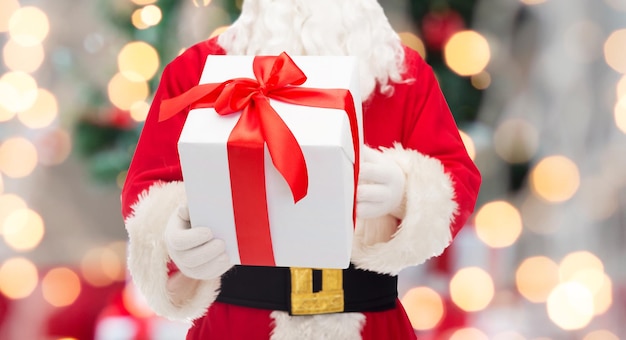 Kerstmis, vakantie en mensen concept - close-up van de kerstman met geschenkdoos over boom lichten achtergrond