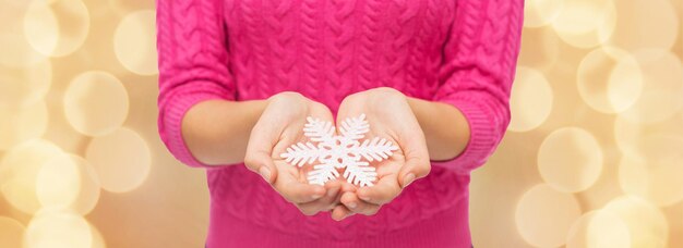 Kerstmis, vakantie en mensen concept - close-up van vrouw in roze trui met sneeuwvlok over beige lichten achtergrond