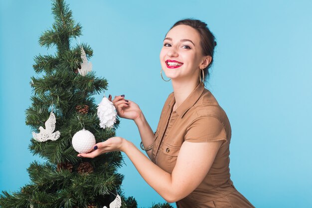 Kerstmis, vakantie en mensenconcept - jong gelukkig meisje dichtbij de kerstboom over blauw