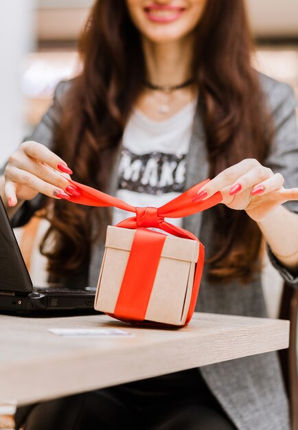 Kerstmis, vakantie, technologie en winkelconcept - lachende vrouw met creditcard op tafel, geschenkdoos en laptopcomputer. Verticale foto