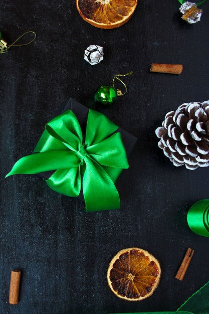 Kerstmisachtergrond met droge oranje, witte dennenappel, groene kerstboomballen, mandarijnen, rode appel, gemberstokken,