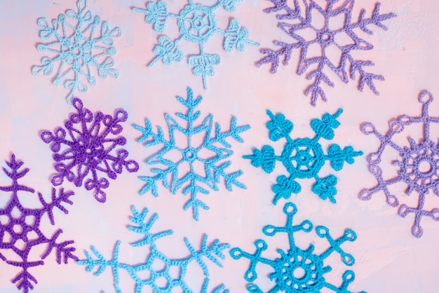 Kerstmisachtergrond met leeg notitieboekje, blauwe gehaakte sneeuwvlok, met de hand gemaakt op een purper-roze achtergrond. gescheurde papieren trend. plat lag, bovenaanzicht. copyspace.