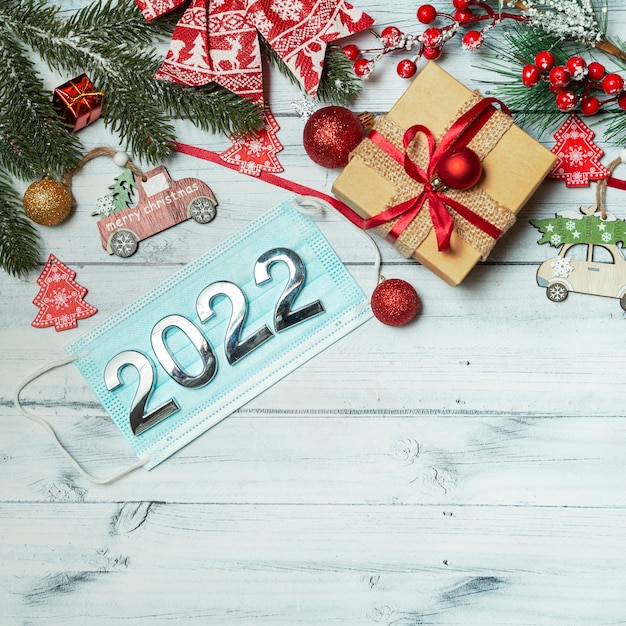 Kerstmisachtergrond met nieuw jaardecoratie medisch masker met aantallen 2022 op houten achtergrond