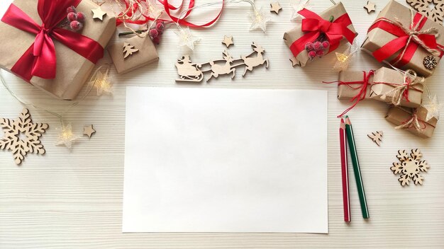 Kerstmisachtergrond met Witboek en potloden op houten tafel met winterdecoraties voor de feestdagen. Wenslijst of plannen voor het jaar. Bovenaanzicht. Ruimte voor tekst.