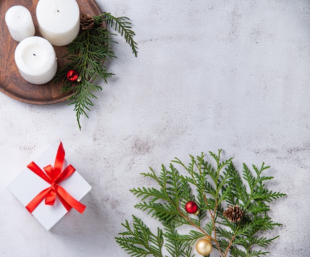 Kerstmisachtergrond met witte huidige doos, kaarsen en thujaboom op lichtgrijze achtergrond. Bovenaanzicht, kopieerruimte, plat leggen