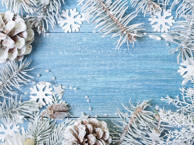 Kerstmisachtergrond met witte nette takken en sneeuwvlokken op een blauwe houten achtergrond