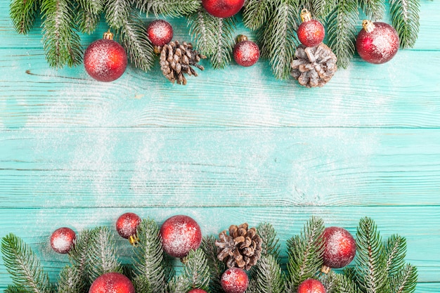Kerstmisbanner met groene boom, rode baldecoratie, kegels op munt houten achtergrond onder sneeuw.