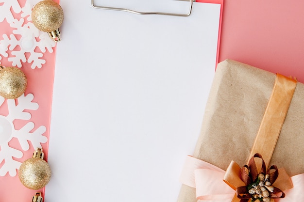 Kerstmisgift in de handen van vrouwen en notitieboekje op een roze, een mening van hierboven