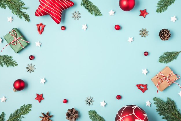 Kerstmiskader van spartakken, giftdozen, suikergoed, rode vakantiedecoratie en denneappels op blauwe achtergrond wordt gemaakt die