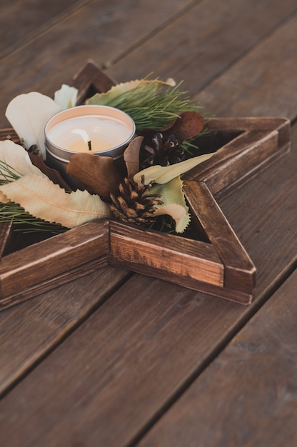Kerstmiskroon in een sterdienblad met een kaars. Mooi decor in rustieke stijl op een houten tafel.
