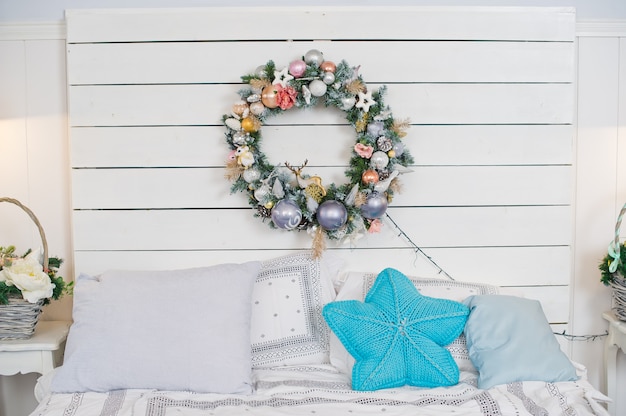 Kerstmiskroon op witte houten muur, beddecor.