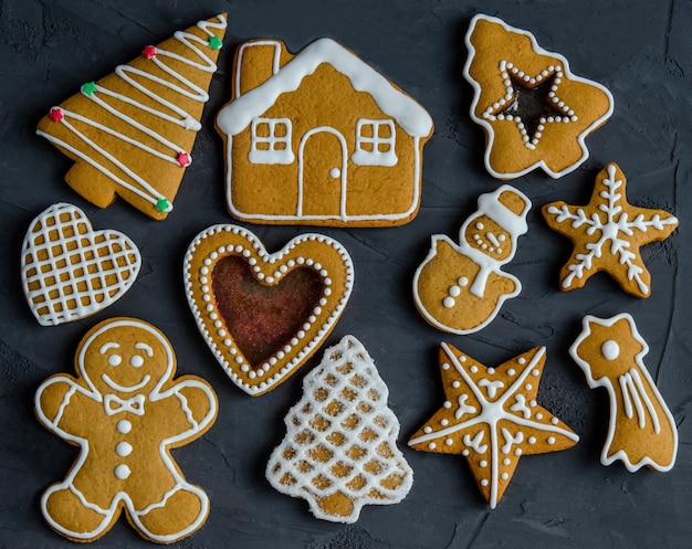 Kerstmispeperkoek met witte die suikerglazuursuiker op een donkere achtergrond wordt geschilderd.