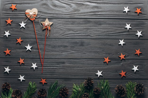 Kerstmissamenstelling: houten grijze achtergrond met spar, denneappels, rode en witte sterren en groot rood houten hart