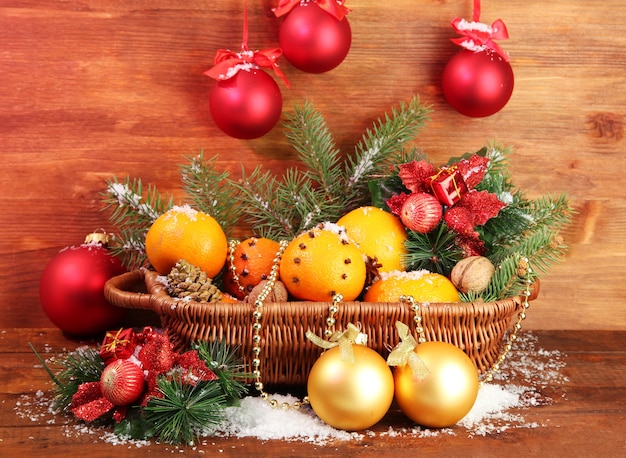 Kerstmissamenstelling in mand met sinaasappelen en dennenboom, op houten achtergrond