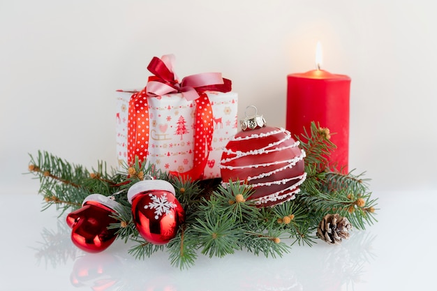 Kerstmissamenstelling met decoratie, giftdozen, rode kaars, kaphandschoenen van Santa Claus en snuisterijen op wit. Kerstvakantie met copyspace.