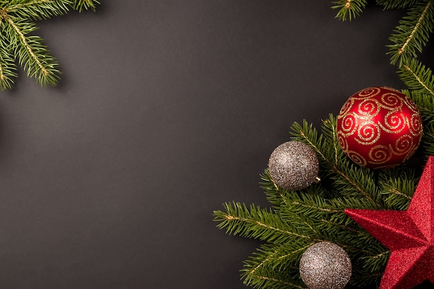 Kerstmissamenstelling met dennentakken, Kerstversieringen en gouden ballen op zwarte achtergrond
