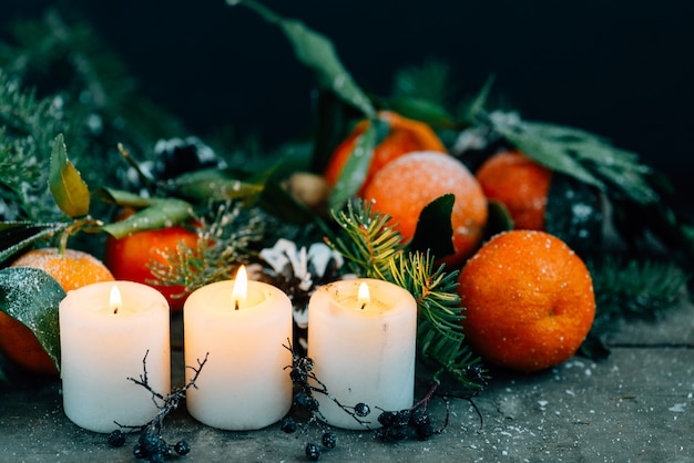 Kerstmissamenstelling met Mandarijnen, Denneappels, Okkernoten en Kaarsen op Houten Achtergrond.