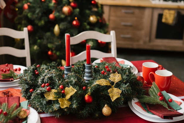 Kerstmissamenstelling met rode kaarsen op een feestelijke lijst met een rood tafelkleed