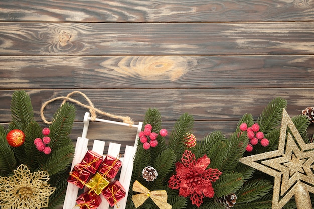 Kerstmisstuk speelgoed slee met sparrentak op een bruine houten achtergrond.