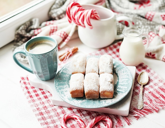 Kerstmuffins, melk, cacao, marshmallows, snoeplollys op plaat bij het raam