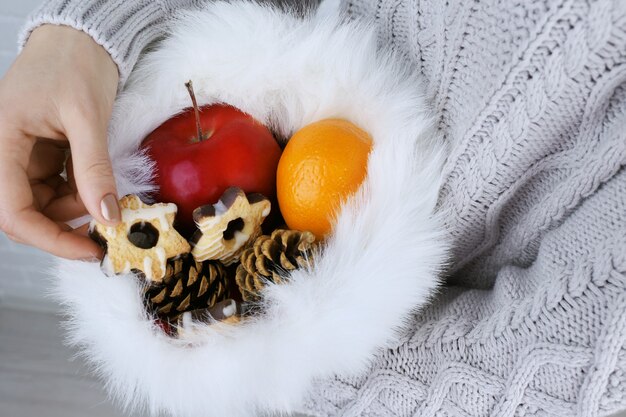 Kerstmuts gevuld met kerstcadeaus in handen van de vrouw