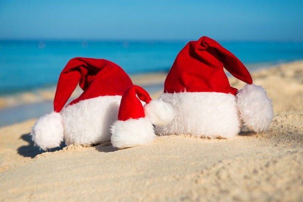 Kerstmutsen op zandstrand - concept van nieuwjaarsvakantie met het gezin met de kinderen aan zee.