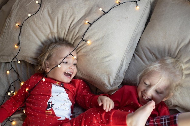 Foto kerstochtend twee kinderen meisjes rode pyjama's plezier bed