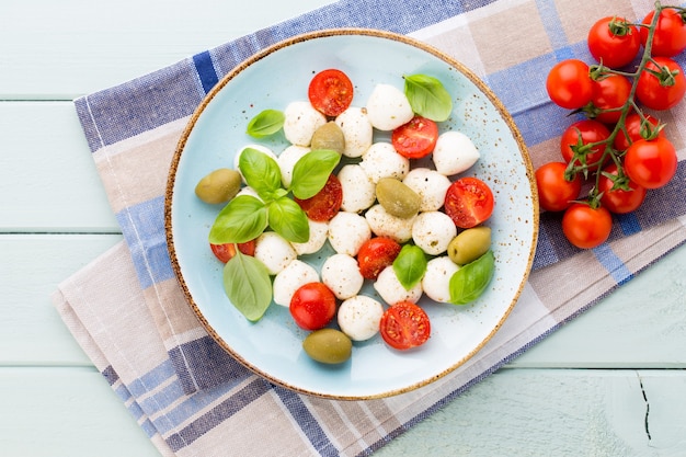 Kerstomaatjes, mozzarellakaas, basilicum en kruiden op grijs leisteen bord. Italiaanse traditionele caprese salade ingrediënten. Mediterraans eten.