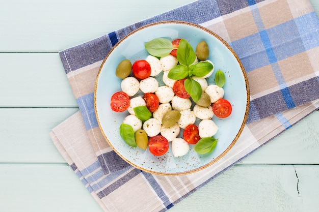 Kerstomaatjes, mozzarellakaas, basilicum en kruiden op grijs leisteen bord. Italiaanse traditionele caprese salade ingrediënten. Mediterraans eten.