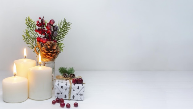 Kerstpanorama Drie kaarsen een doos met een kerstcadeau van de kerstman en een dennenboom met een dennenappel Geweldige kerstkaart