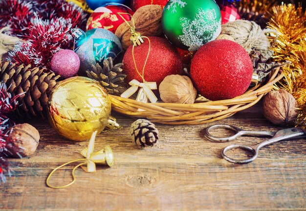 Kerstsamenstelling met geschenken. Mand, rode ballen, dennenappels, sneeuwvlokken op houten tafel. Vintage-stijl