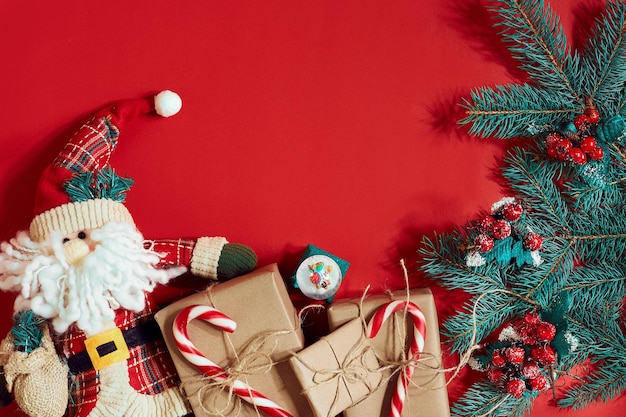 Kerstsamenstelling van dennenappels vuren takken en stapel geschenkdozen op rode achtergrond