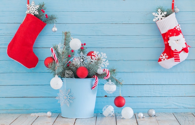 Kerstsok en dennentakken in blauwe buchet op blauwe houten muur