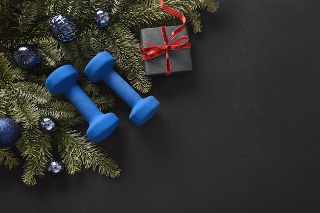 Kerstsportcompositie met blauwe sporthalters cadeau dennentakken en kerstcadeau