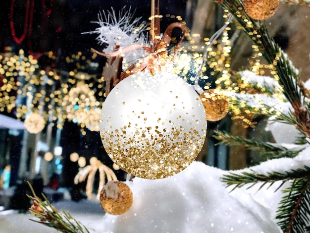 Kerststad decoratie dennenboomtak met witte bal en verlichting, avond stadslicht