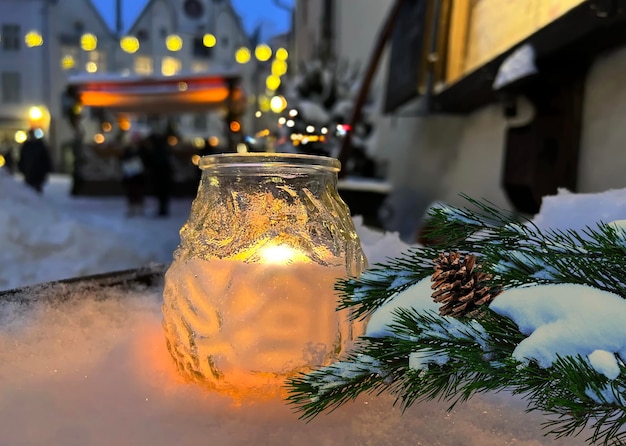 Kerststad middeleeuws straatkaarslicht, dennenboom met kegel onder sneeuw, 's avonds wazig licht